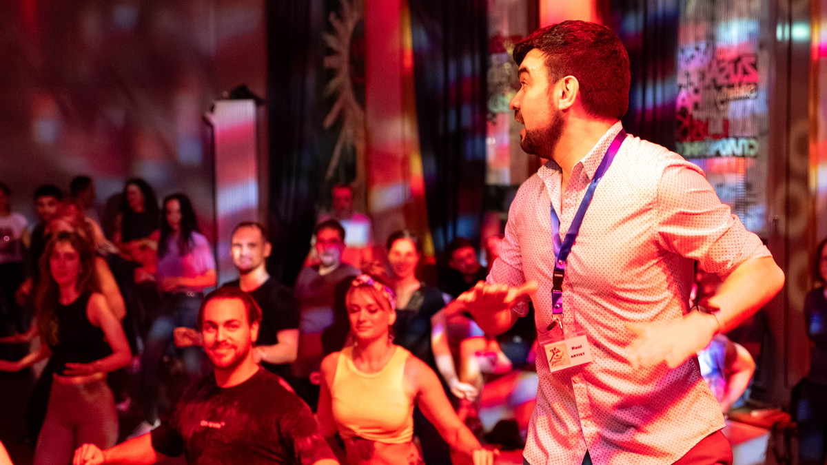 Foto einer Salsa- und Bachata-Party mit vielen tanzenden Menschen und einem Tanzlehrer im Vordergrund
