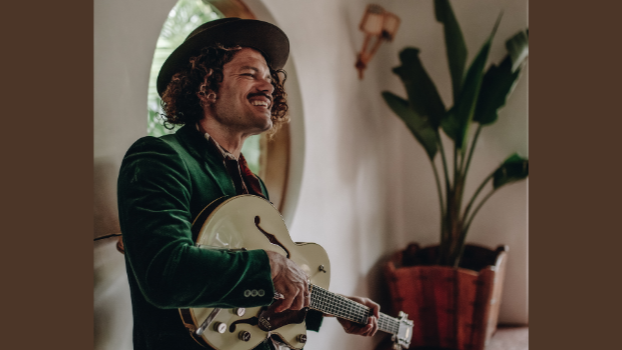 Ash Grunwald steht mit einer Gitarre vor der Kamera