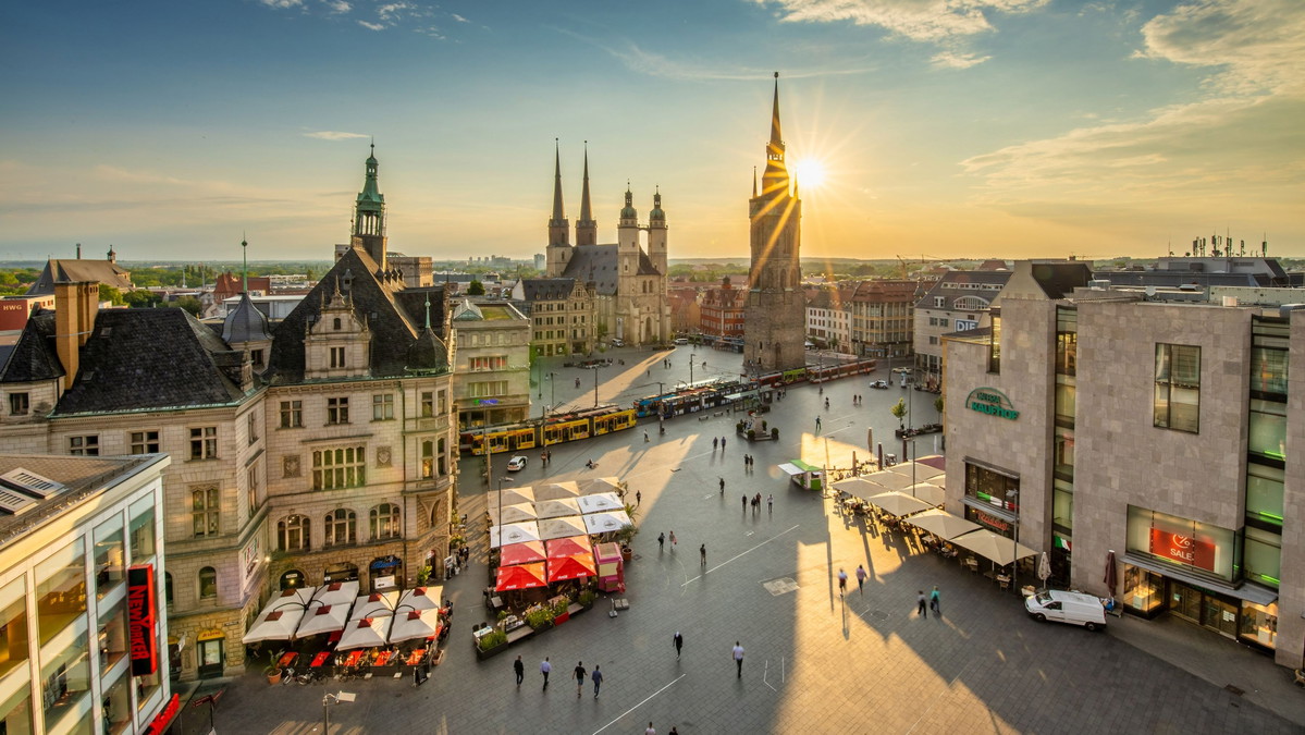 Blick über den Marktplatz von Halle (Saale) bei Sonnenuntergang. Der rote Turm und die Marktkirche sind zu sehen.