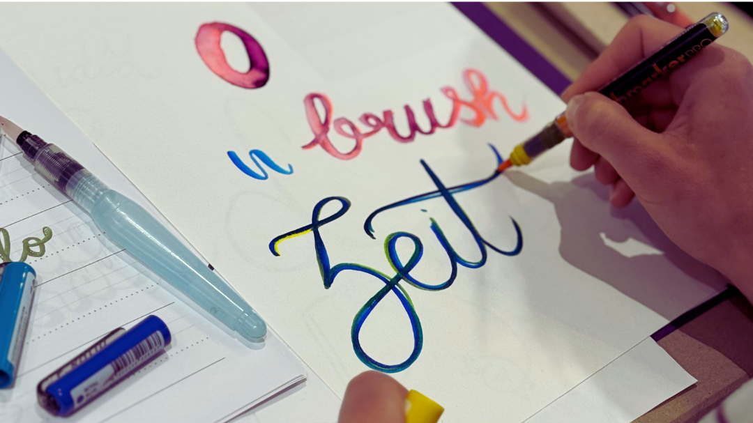 Person schreibt mit einem Pinselstift ein Lettering